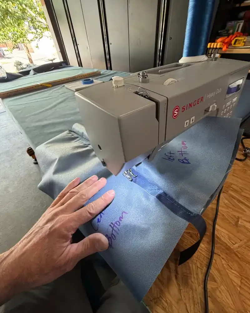 Jerred Lane sewing a prototype mat panel on a heavy-duty sewing machine in the workshop.